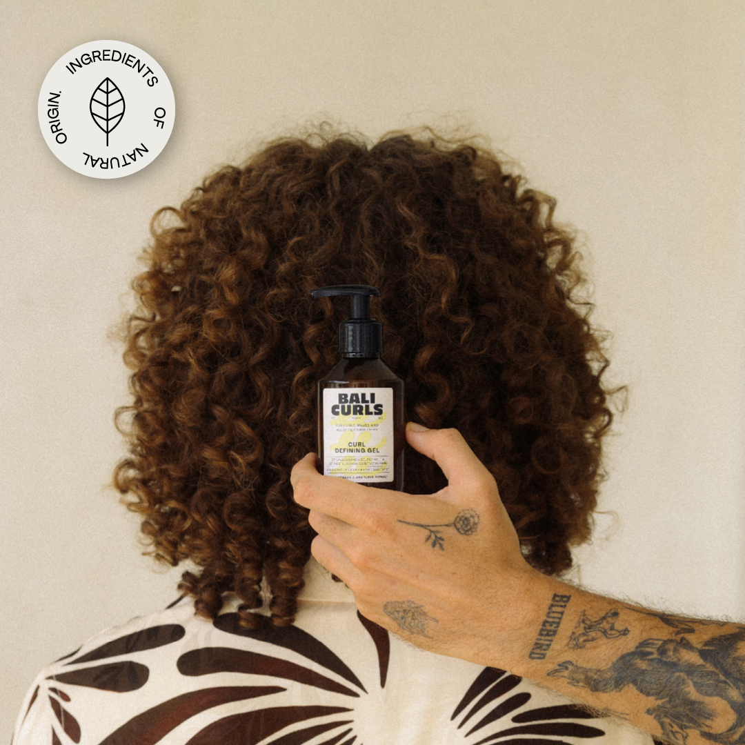 Abbildung des Hinterkopfes eines Mannes mit Lockigem Haar, dem Bali Curls Curl Defining Gel in der Hand eines Tätowierten Mannes davor und einem: "Ingredients of Natural Origin." Sicker in der Rechten oberen Ecke