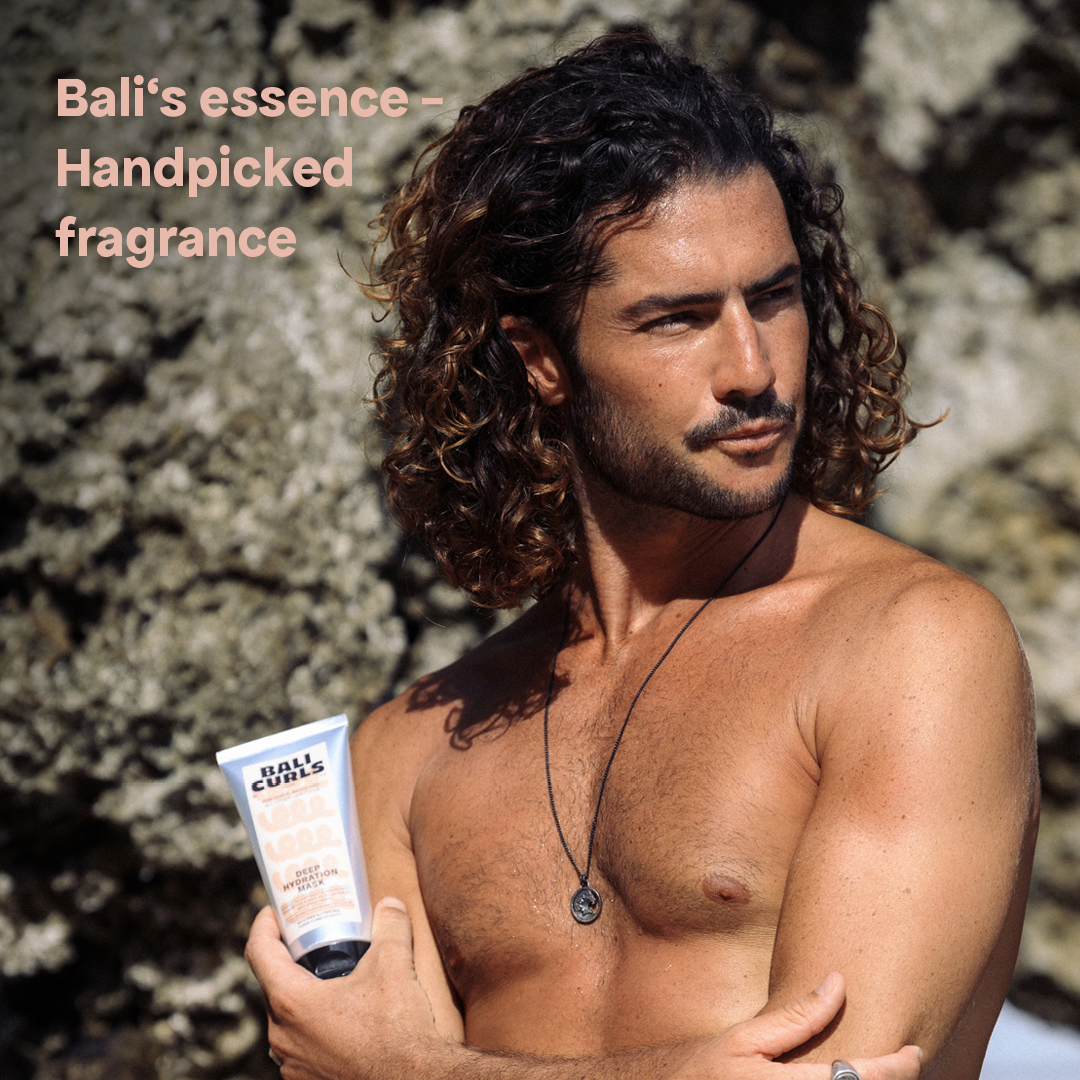 Abbildung eines Oberkörperfreien Mannes mit schönem Lockigem Haar, Bart, Kette vor Steinfelsen, der Bali Curls Deep Hydration Mask in der Hand und der Überschrift: "Bali´s essence - Handpicked fragrance" in der linken oberen Ecke