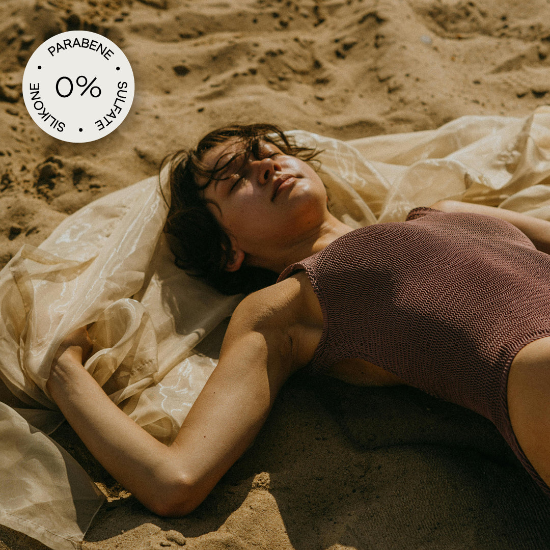 Abbildung einer Frau, die am Strand mit einem Seidentuch in der Sonne liegt und einem: "0% Parabene, Sulate und Silikone" Sticker in der linken oberen Ecke