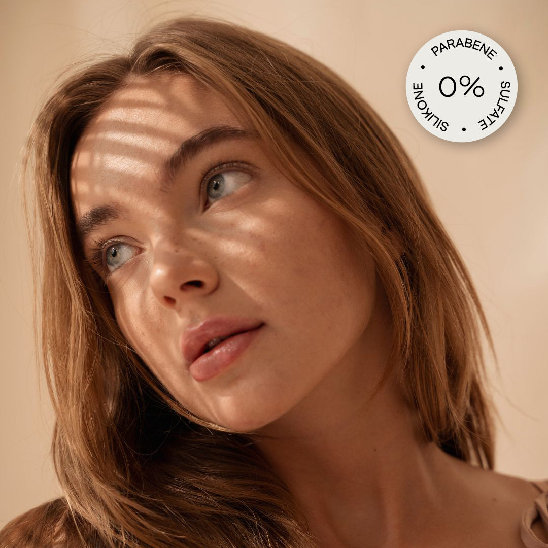 Abbildung einer Schönen Frau mit Sonnenstrahlen im Gesicht und einem: "0% Parabene, Sulafate und Silikone" Sticker in der rechten oberen Ecke