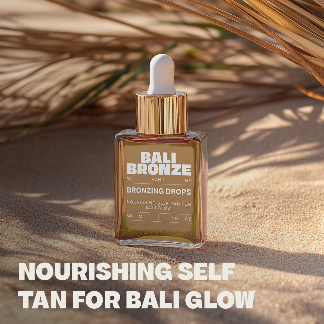 Bali Bronze Bronzing Drops Produktabbildung im Sand mit Palmenblatt im Hintergrund und dem Schriftzug: "Nourishing Self Tan for Bali Glow" darunter